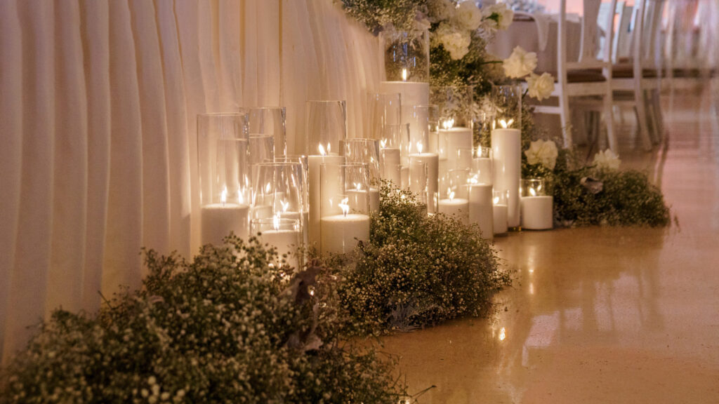 Montaje de cera de arena en cilindros de cristal delante de la mesa de los novios de una boda